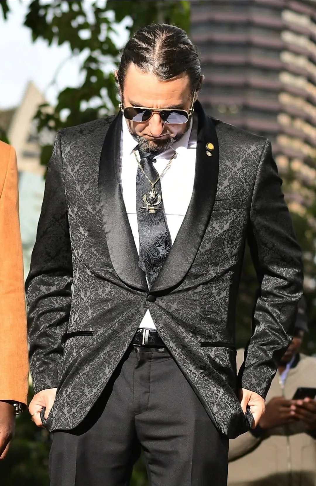 Eliahi outdoors, wearing sunglasses and a suit